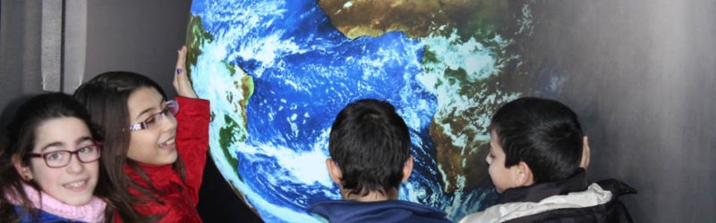 niños observando gran bola terrestre